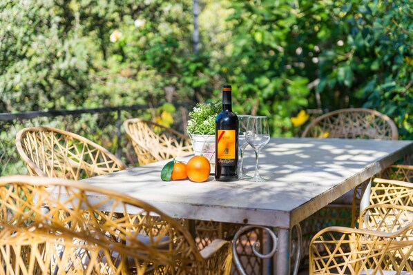 A table with a bottle of wine, two glasses, and two oranges.