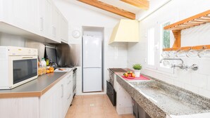 A modern kitchen with white cabinetry, a microwave, a stove, a refrigerator, and a granite countertop. - House with Pool and Sea Views - Casa Can Divertit (Can Budella)