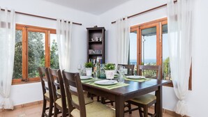 A dining area with a wooden table, chairs, and a bookshelf. - House with Pool and Sea Views - Casa Can Divertit (Can Budella)