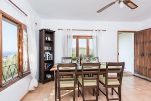 Un coin repas comprenant une table, des chaises, une bibliothèque et une vue par la fenêtre.