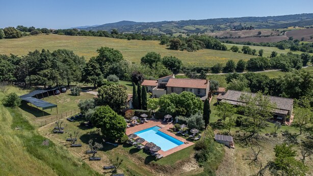 An aerial view of a property with a swimming pool, outdoor seating, and a large garden.