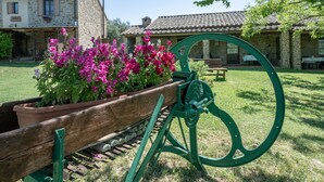A rustic stone building with a wooden bench and a green mechanical device in a garden.