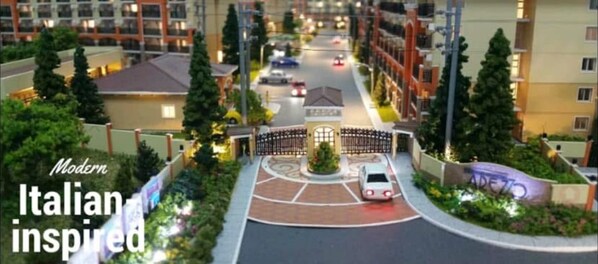 Un complexe résidentiel moderne, d’inspiration italienne, comprenant un rond-point central, plusieurs bâtiments et une entrée sécurisée.