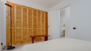 Un dormitorio con cama, armario de madera y una banca.