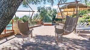 A hammock chair under a tree, a pool, and a lounge area with umbrellas. - Holiday Apartment 'mamuthones' with Sea View, Wi-Fi, Terrace & Shared Pool (Orosei)