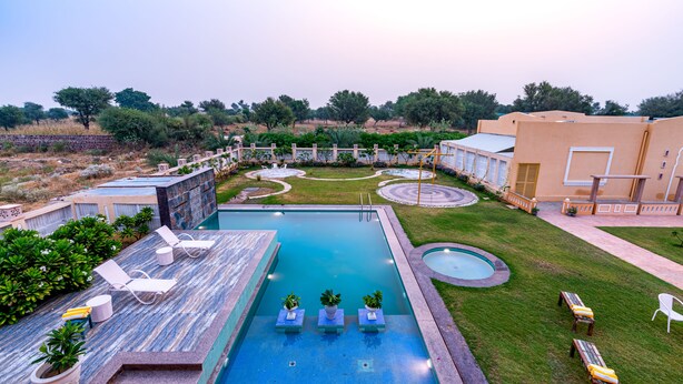 A swimming pool with lounge chairs and a small garden area.