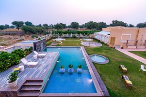 A swimming pool with lounge chairs and a small garden area.