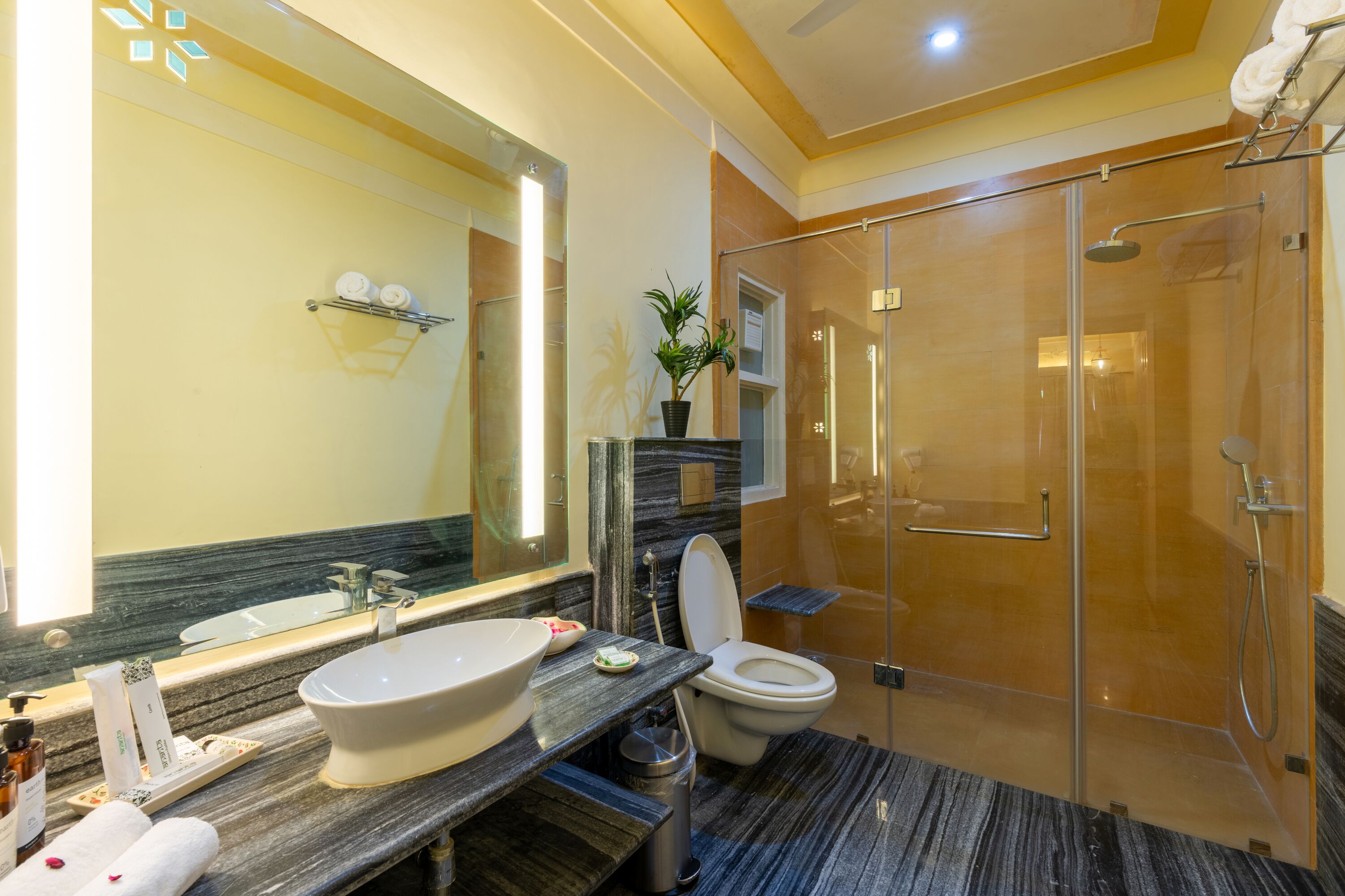 A modern bathroom with a large mirror, a sink, a toilet, and a glass-enclosed shower area.