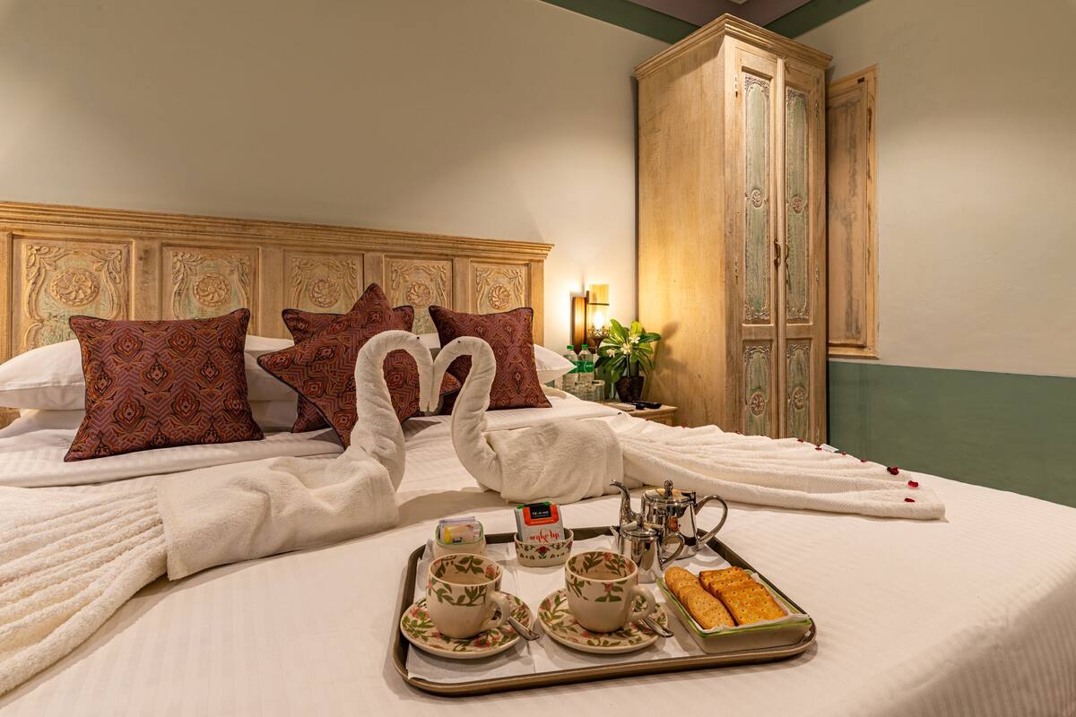 A neatly made bed with a tray of breakfast items, including tea cups and pastries.