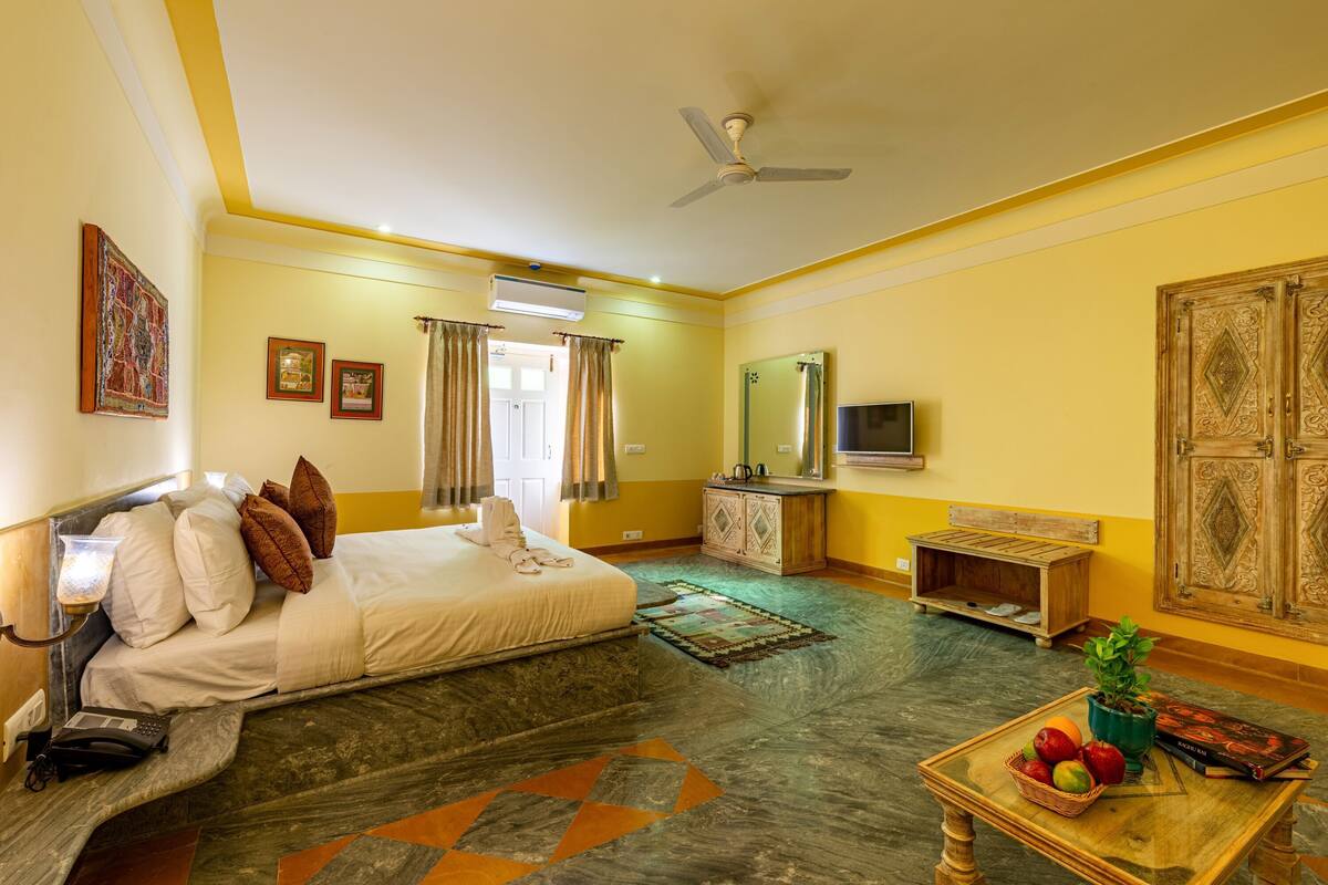 A hotel room with a bed, a desk, a television, and a window with curtains.