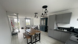 Una cocina moderna con una mesa de comedor de madera, armarios grises e iluminación colgante.