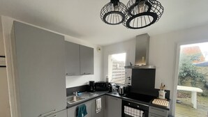 Una cocina moderna con armarios grises, una estufa negra y una ventana con vistas a un jardín.