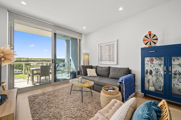 A modern living room with a sofa, coffee table, and a cabinet with decorative items.