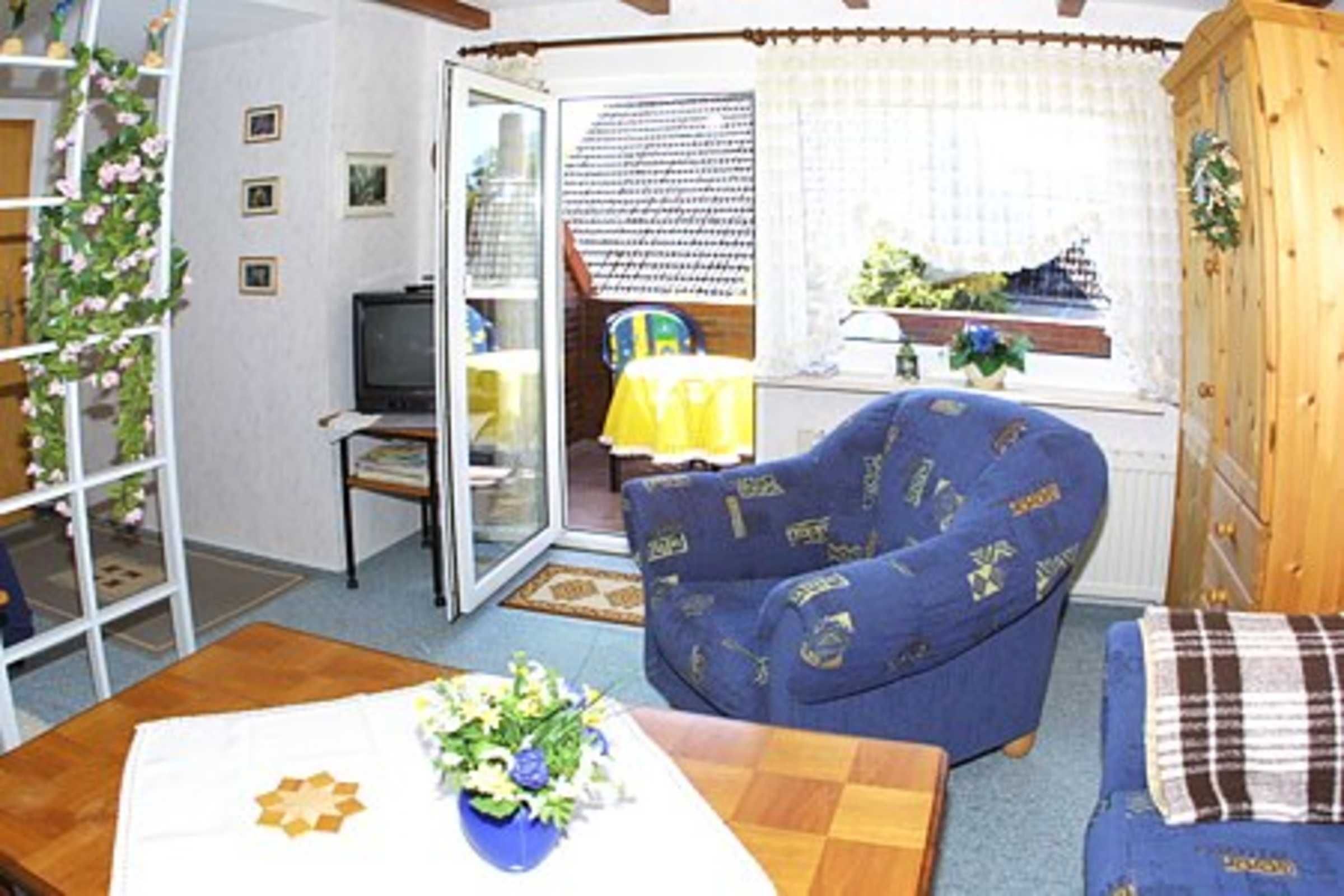Una sala de estar con un sofá azul, un aparador de madera y un televisor.