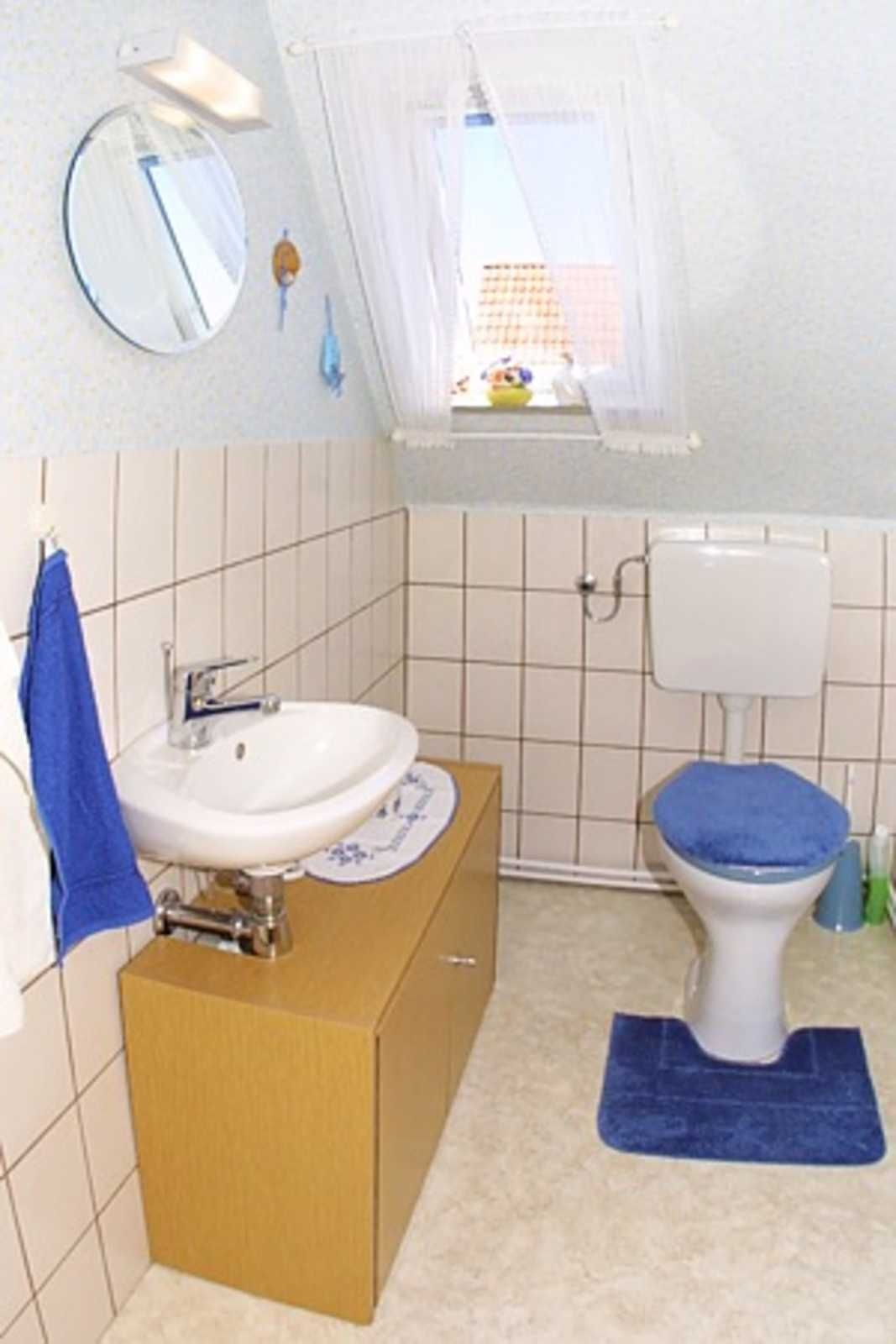 Ein Badezimmer mit Waschbecken, Toilette und einem Fenster mit Blick auf Gebäude.