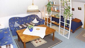 Ett vardagsrum med en soffa, ett soffbord, en bokhylla och en stege.