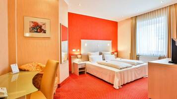Een hotelkamer met een rood tapijt, twee bedden, een bureau en een televisie.