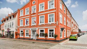 A red building with multiple windows and flags, labeled as a hotel and restaurant.