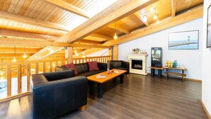 A spacious living area with a wooden ceiling, a fireplace, a sofa, and a coffee table.