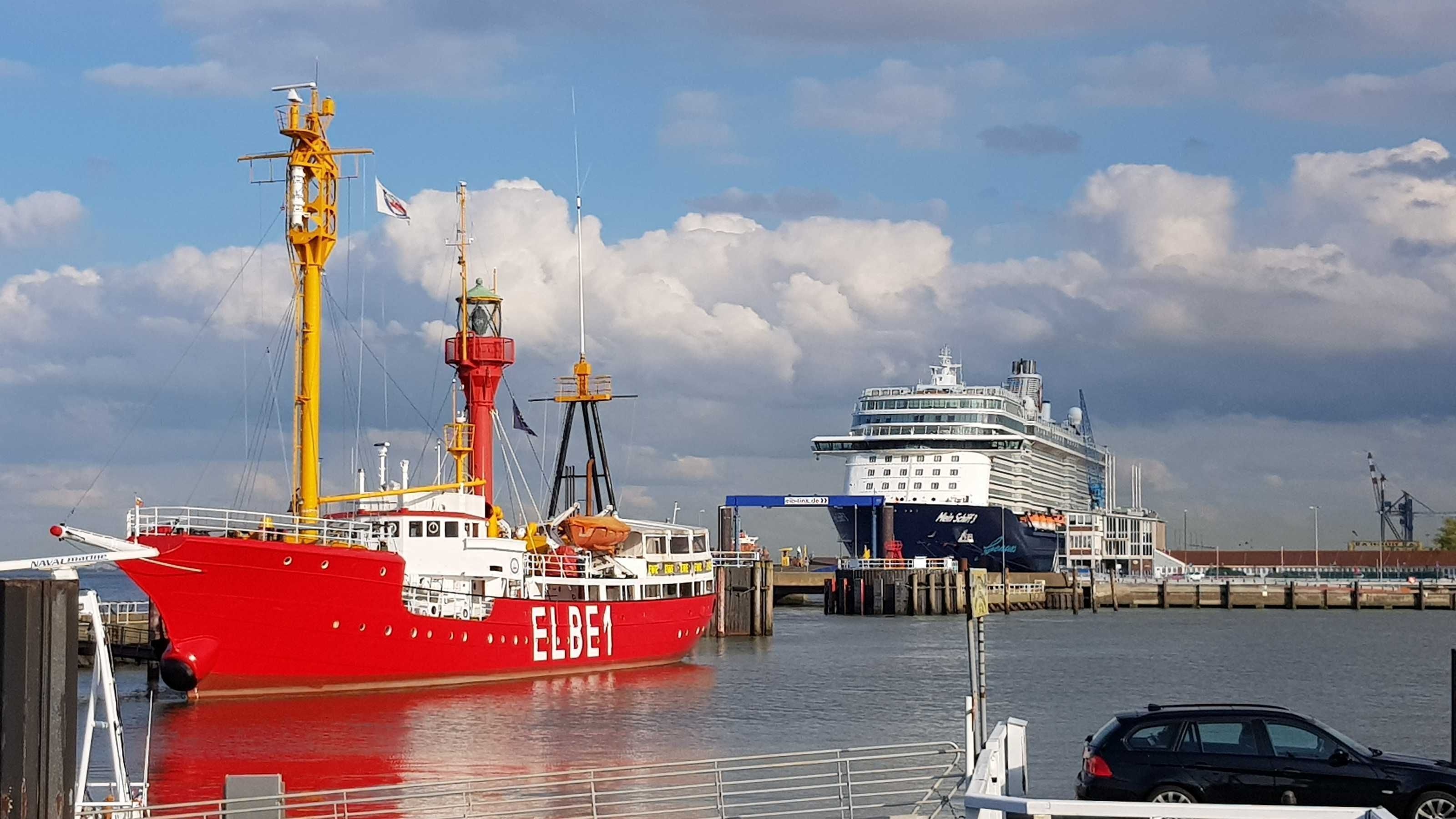 Un cargo rouge était amarré à un port, avec un grand navire de croisière en arrière-plan.