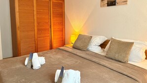 Una camera d'albergo con un ampio armadio in legno, un letto con lenzuola bianche e un quadro appeso al muro.