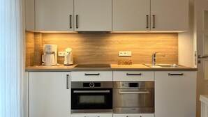 Una cucina moderna con mobili bianchi, una schiena di legno, una macchina da caffè, un lavello e due forni Bosch.