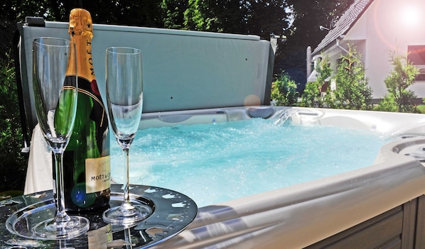 A hot tub with two champagne glasses and a bottle.