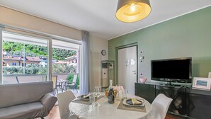 Ein Essbereich mit Tisch für zwei Personen, einer Couch, einem Fernseher und Blick ins Freie.