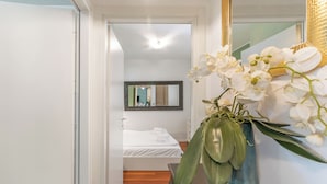 Ein Hotelzimmer mit einem Bett, einem Spiegel, einer Orchideen-Vase und einem Holzboden.