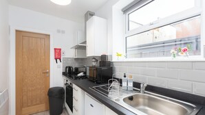 Una cucina moderna con mobili bianchi, un lavello in acciaio inossidabile e una finestra che si affaccia su edifici.