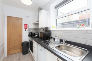 A modern kitchen with white cabinets, a stainless steel sink, and a window with a view of buildings.