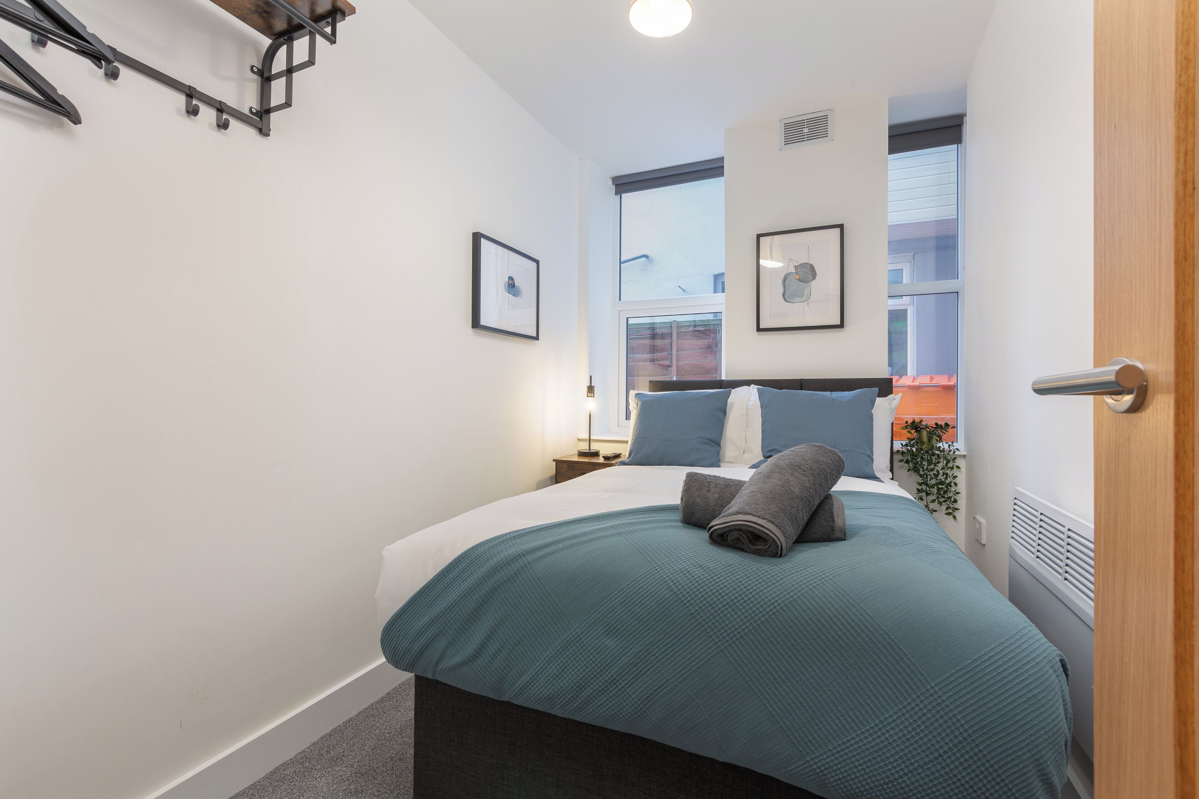 Un dormitorio moderno con cama, mesita de noche, ventana y puerta.