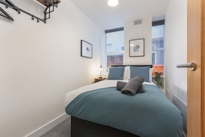 Une chambre à coucher moderne avec un lit, une table de chevet, une fenêtre et une porte.