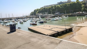 A marina with multiple boats docked, a concrete dock, and a building in the background. - 13 Lyndhurst Avenue (Kilgetty)