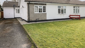 A single-story house with a white exterior, a red bench, and a paved driveway. - 13 Lyndhurst Avenue (Kilgetty)