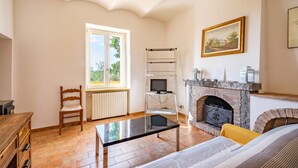 A living room with a fireplace, a television on a stand, a wooden chair, and a table. - APARTMENT 6 PEOPLE IN COUNTRY VILLA WITH POOL (Lame)