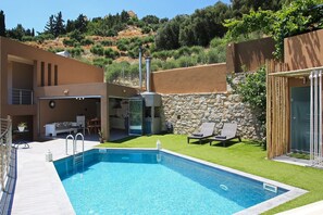 A modern house with a swimming pool, a stone wall, and a grassy yard. - Design Villa Nicol Heated Pool Seaview (Malevizi)