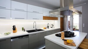 A modern kitchen with white cabinetry, a stainless steel range hood, and a built-in dishwasher. - Design Villa Nicol Heated Pool Seaview (Malevizi)