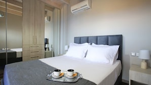 A hotel room with a bed, bedside lamps, a tray with cups and pastries, and an air conditioning unit. - Design Villa Nicol Heated Pool Seaview (Malevizi)