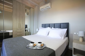 A hotel room with a bed, bedside lamps, a tray with cups and pastries, and an air conditioning unit. - Design Villa Nicol Heated Pool Seaview (Malevizi)
