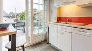 A modern kitchen with white cabinets, a red backsplash, and a built-in dishwasher. - Charming house in Granville with garden and terrace (Granville)