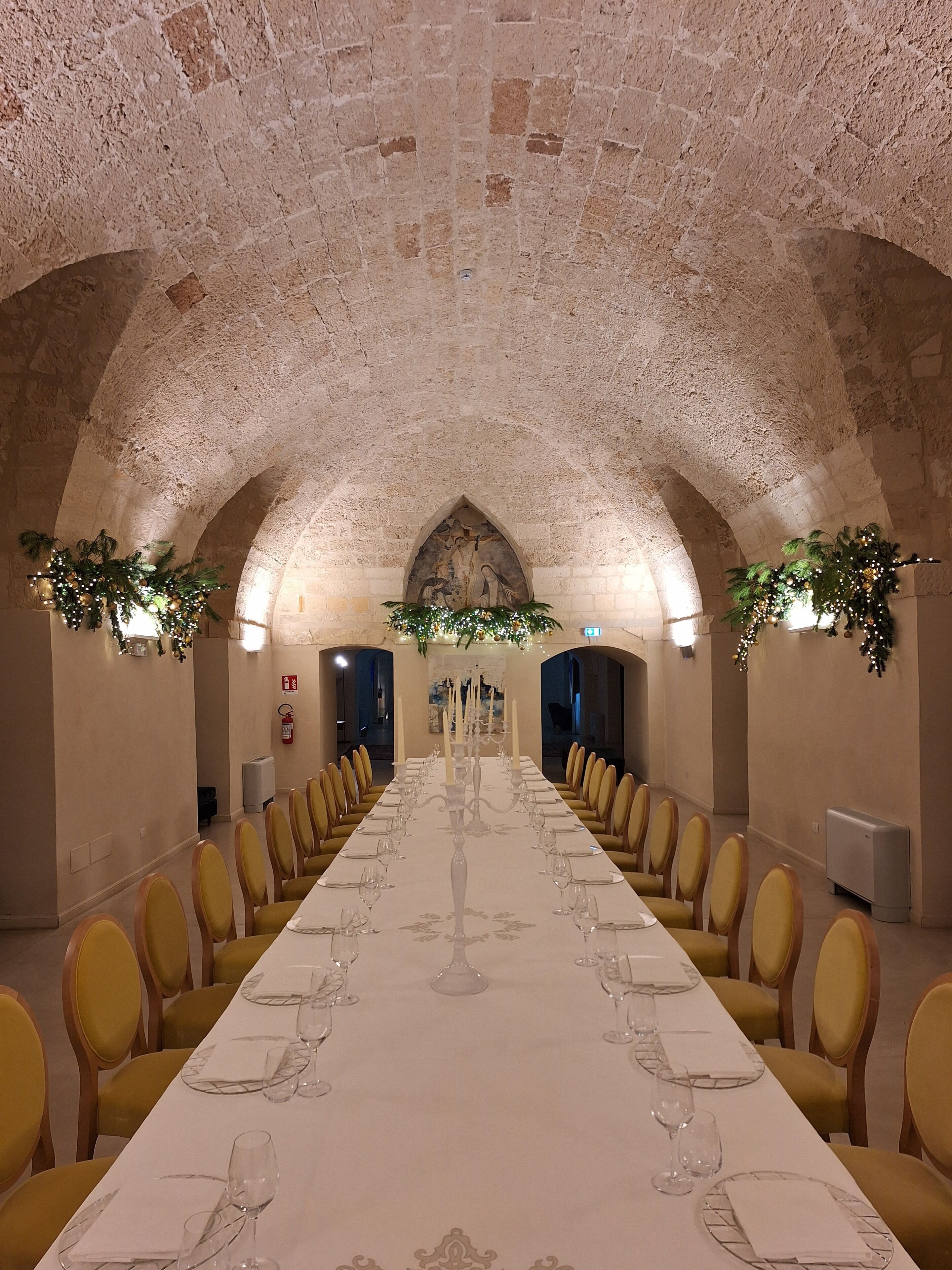 A long dining table with chairs, candles, and a mural on the wall.