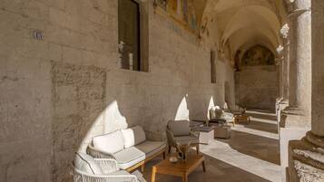 A sunlit interior with a stone wall, a sofa, a coffee table, and a chair.