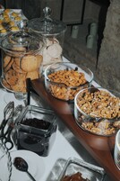 A buffet with various food items in clear containers, including cookies, almonds, and a dark spread.