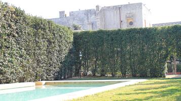 A swimming pool with a hedge and a building in the background.