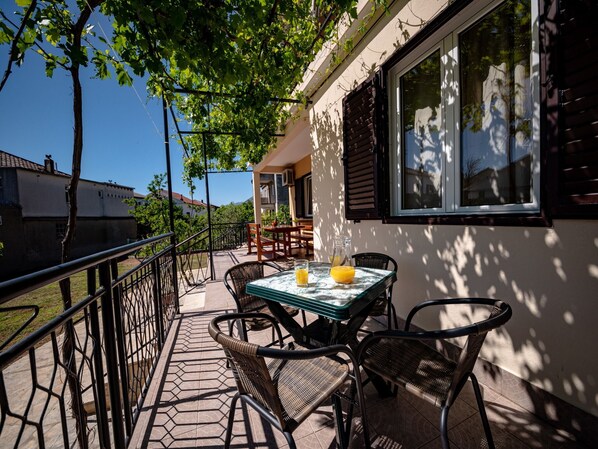 Una terraza con una mesa, sillas, una ventana y una barandilla.