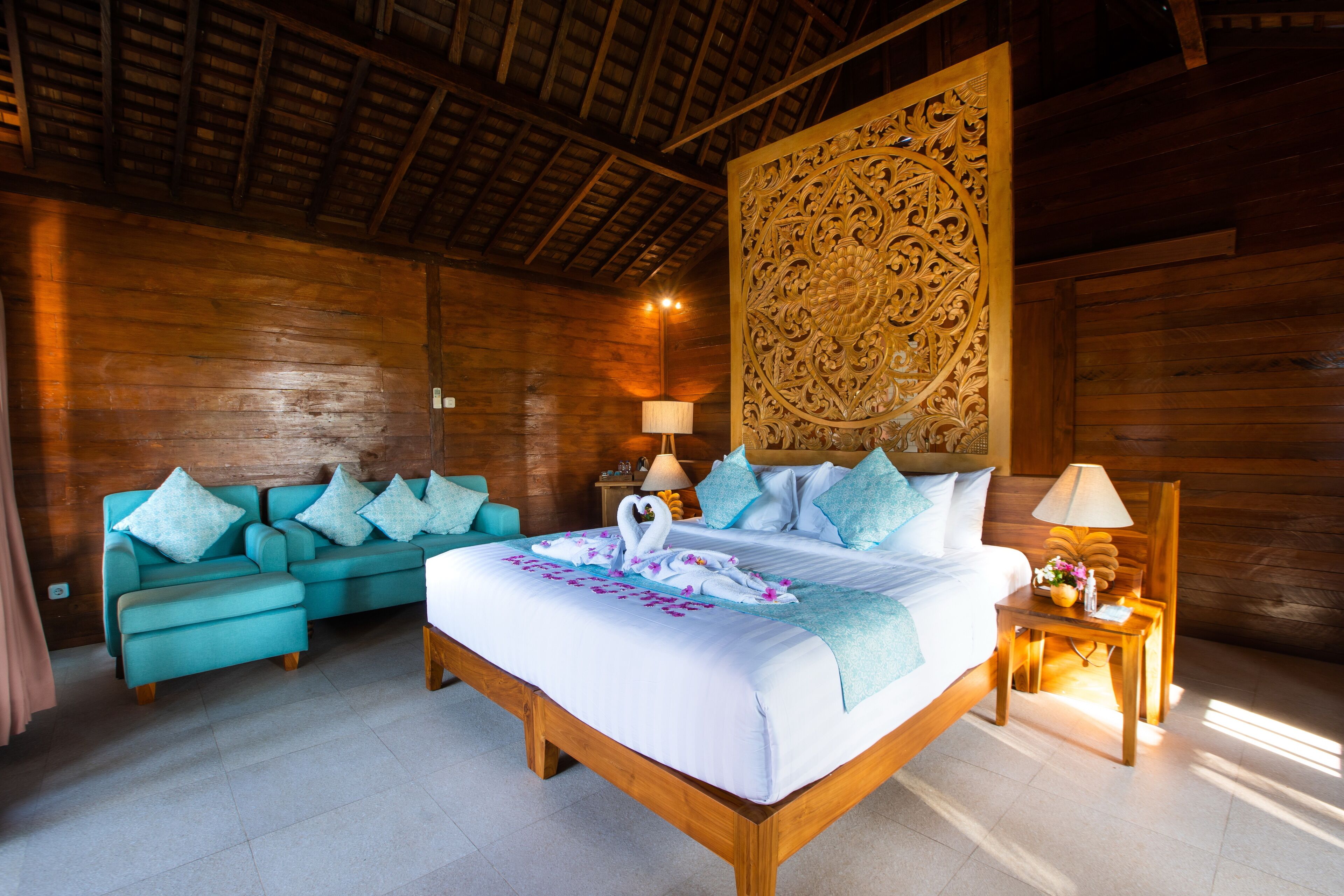 A wooden room with a bed, a sofa, and a decorative wall panel.