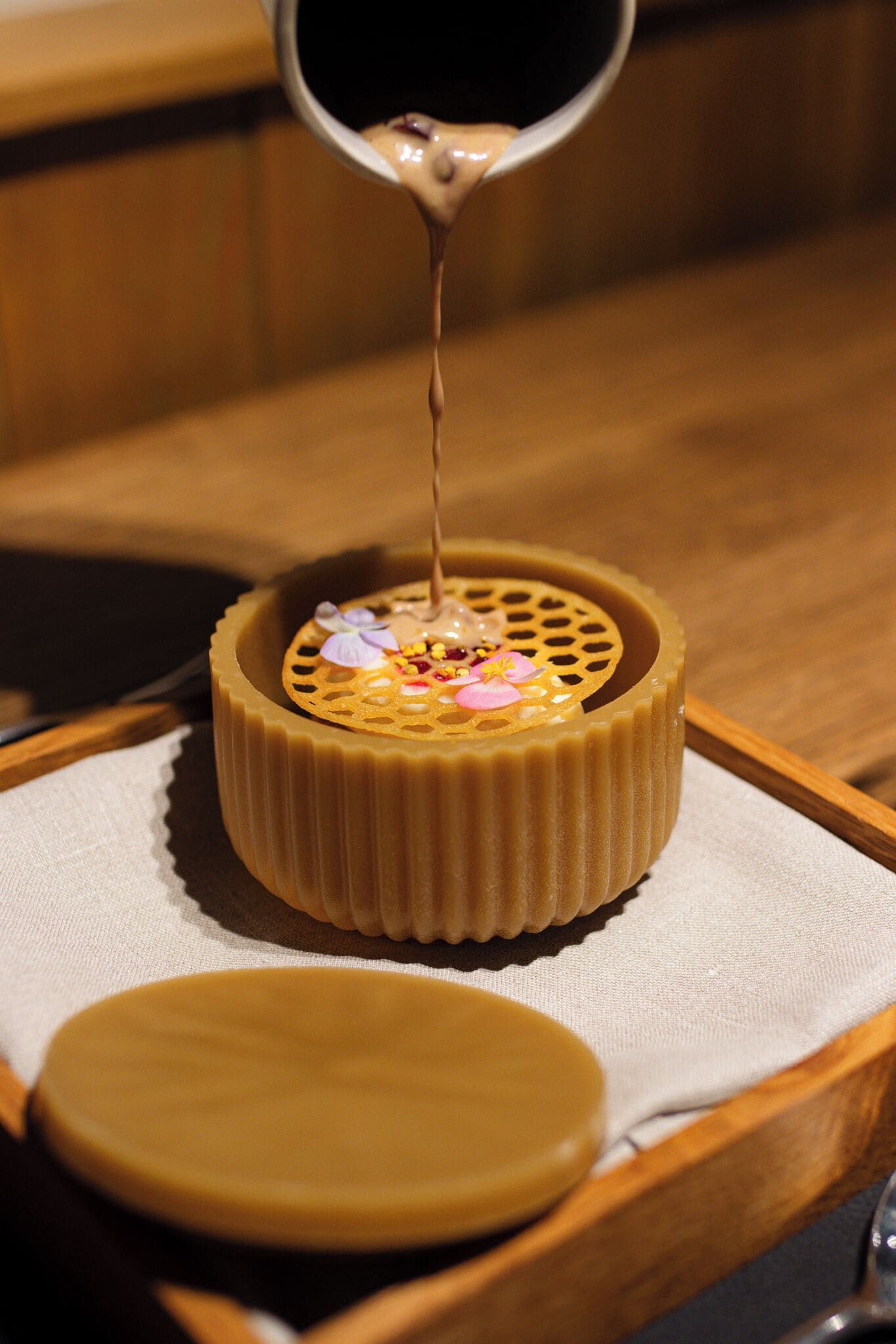 Un dessert surmonté d  ’une crème onctueuse, présenté sur un plateau en bois avec une nappe en dessous.