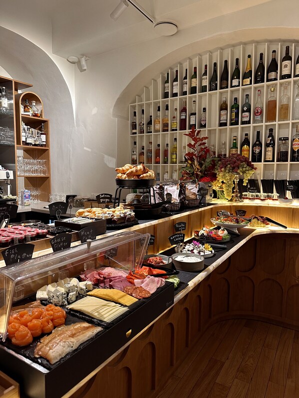 A buffet area with various food options and a wine shelf in the background. - Dome Hotel (Riga)