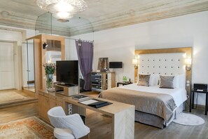 A modern hotel room with a large bed, a desk with a chair, a TV, and a wardrobe. - Dome Hotel (Riga)